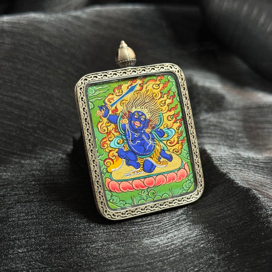 Angled view of Acalanatha (Fudo Myo-o) miniature thangka pendant showing the fierce Wisdom King holding a sword amid flames in traditional Himalayan Buddhist painting.