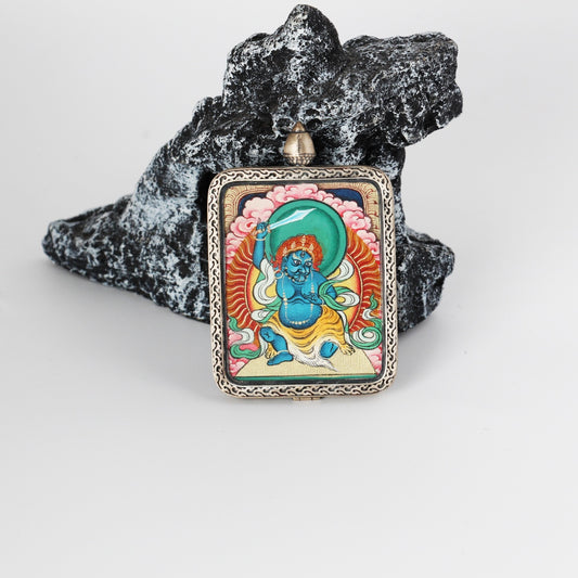 Front view of Acalanatha (Fudo Myo-o) mini Thangka pendant, hand-painted with mineral pigments, featuring a vivid turquoise-green halo, flaming aureole details, and an engraved pure silver frame.