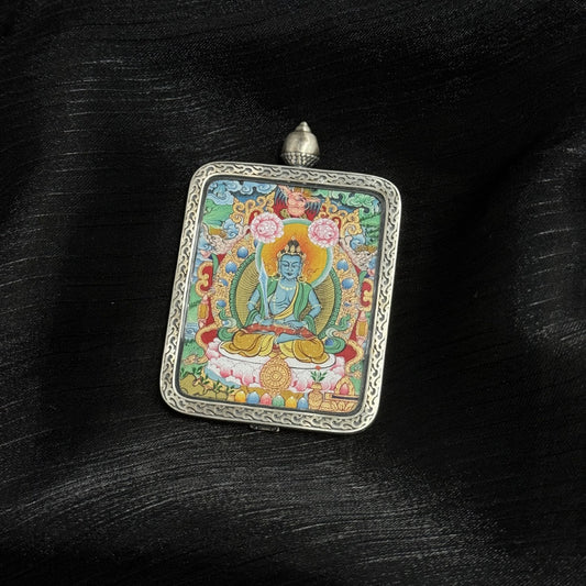 Angled view of Akasagarbha Bodhisattva thangka pendant showing mineral pigment layering, detailed halo pattern, lotus base, offering motifs, and engraved silver frame with top loop.