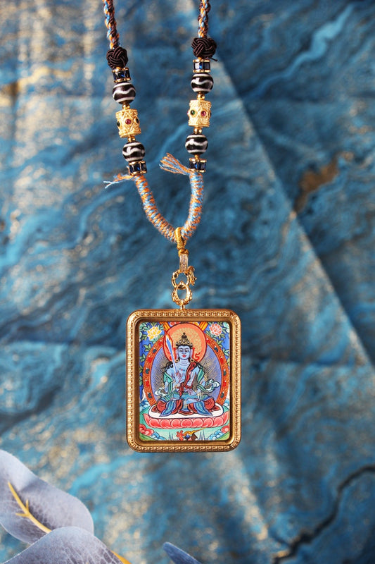 Close-up of the Akasagarbha Bodhisattva mini thangka pendant highlighting fine linework, saturated mineral pigment colors, lotus seat details, ornate border pattern, and the beadwork near the pendant loop.