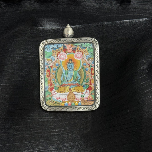 Front view of Akasagarbha Bodhisattva mini thangka pendant, hand-painted with mineral pigments, seated on lotus throne with halo, enclosed in Dunhuang Nine-Colored Deer silver gawu case with engraved border.