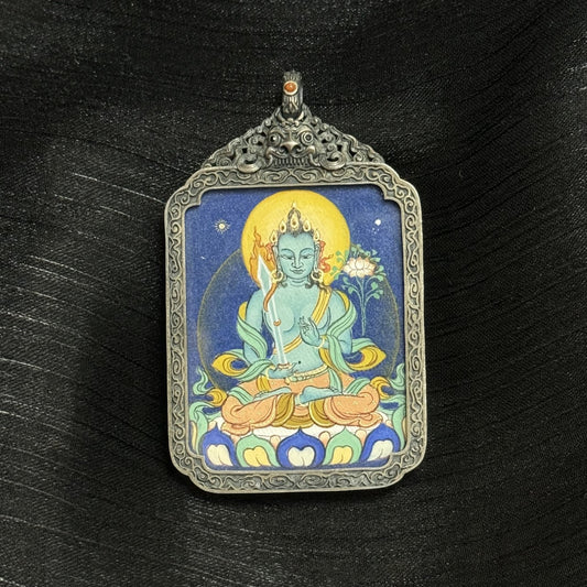 Angled view of Akasagarbha Bodhisattva mini thangka pendant, hand-painted with natural mineral pigments, set in an ornate vintage silver case with carved details.