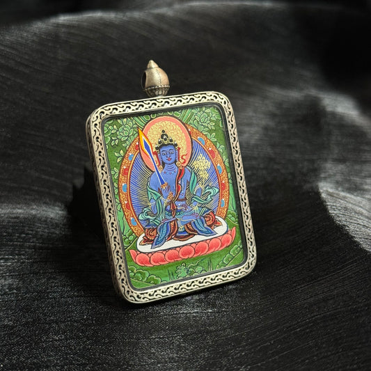 Angled view of Akashagarbha Bodhisattva thangka pendant highlighting intricate mineral pigment painting, green background composition and traditional Tibetan silver frame