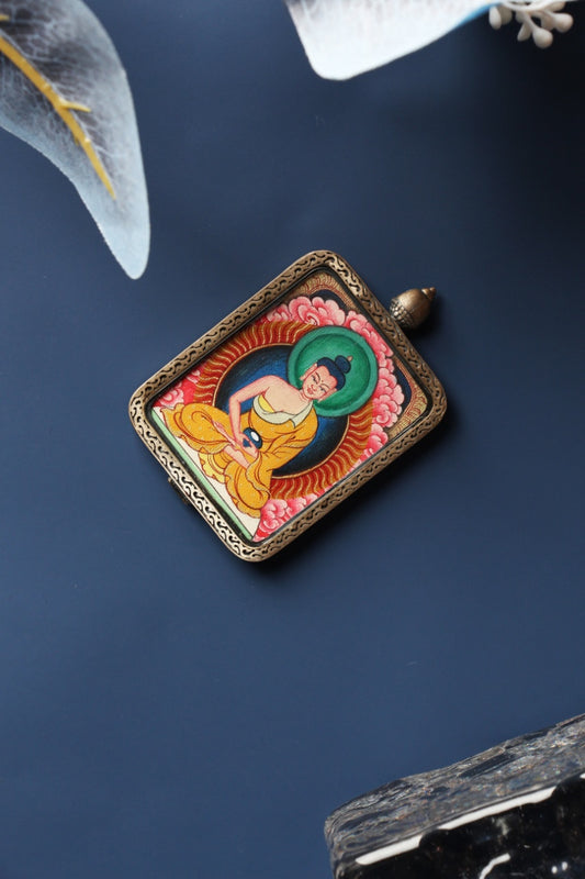 Angled product view of the Amitabha Buddha mini thangka pendant from the Tibetan Red Cloud Zangka Series, fully hand-painted in Tibet with natural mineral pigments and presented in a Dunhuang Nine-Colored Deer sterling silver case for portable devotion and collecting.