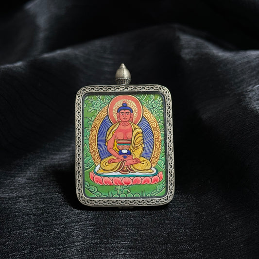 Front view of Amitabha Buddha mini thangka pendant, hand-painted with natural mineral pigments in Rebgong style, showing the Buddha seated on a lotus throne within an ornate silver pendant frame
