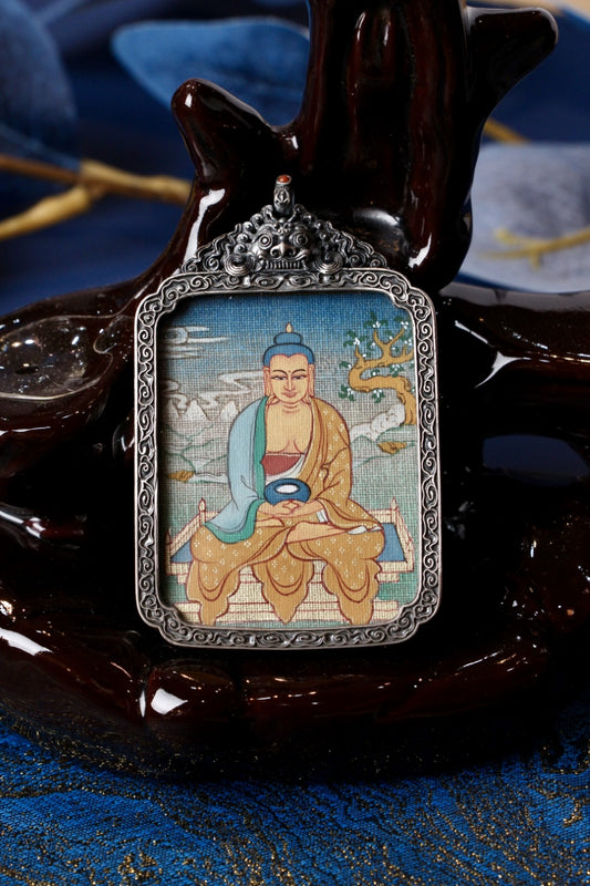 Close-up of an ornate vintage silver gawu pendant with a hand-painted Amitabha Buddha mini thangka, displayed on a dark wood stand.