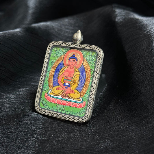 Angled view of Amitabha Buddha thangka pendant highlighting detailed mineral pigment painting, lotus seat composition and traditional Tibetan silver frame