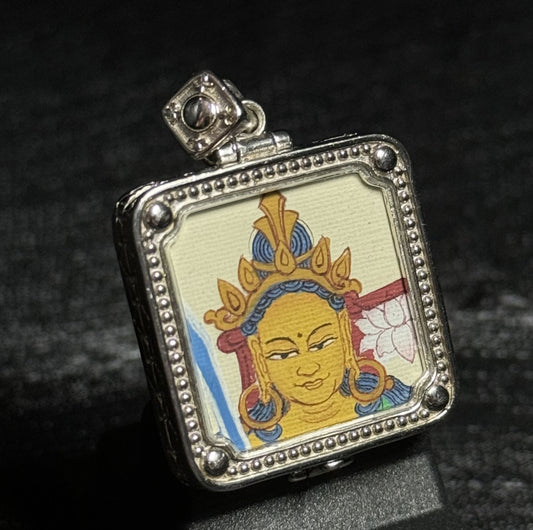 Angled view of a miniature Manjushri Bodhisattva thangka pendant highlighting the hand-painted deity portrait and textured silver pendant frame.