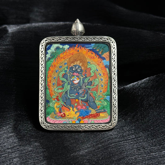 Front view of Black Jambhala mini thangka pendant, fully hand-painted with mineral pigments and gold powder, set in an ornate silver frame with detailed Tibetan deity artwork