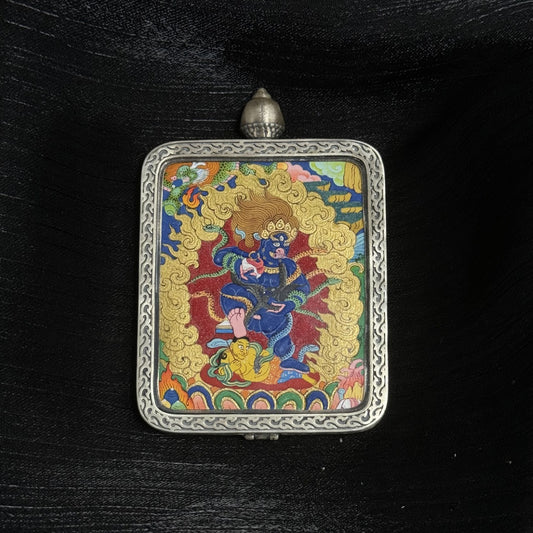Hand-painted Black Jambhala mini thangka pendant in a square silver gawu case, featuring the wrathful wealth deity standing in a dynamic posture surrounded by golden flames, detailed mineral pigment painting on canvas with traditional Tibetan iconography.