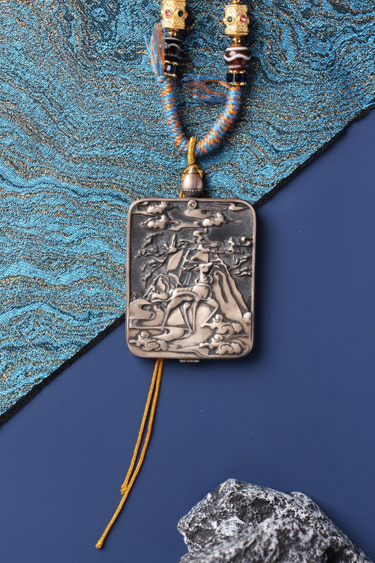 Back view of the Vajrasattva pendant showing a deer-embossed silver case with detailed relief carving and hanging tassel.