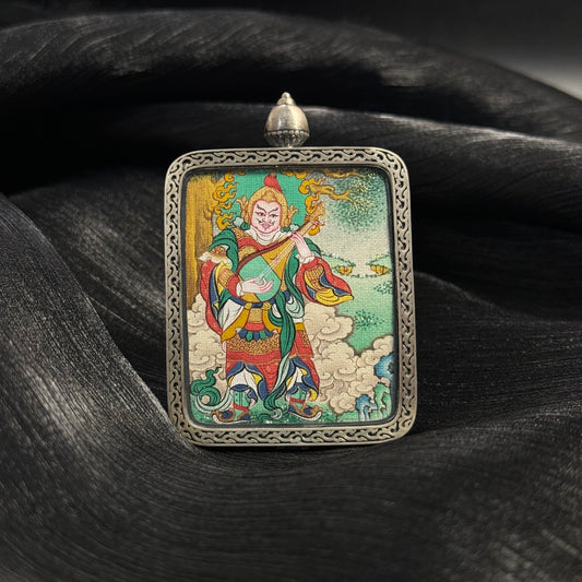 Front view of Dhṛtarāṣṭra Eastern Guardian King mini thangka pendant, hand-painted Tibetan deity holding a pipa, mounted in a 925 sterling silver relief frame with intricate border details and vibrant mineral pigment painting.