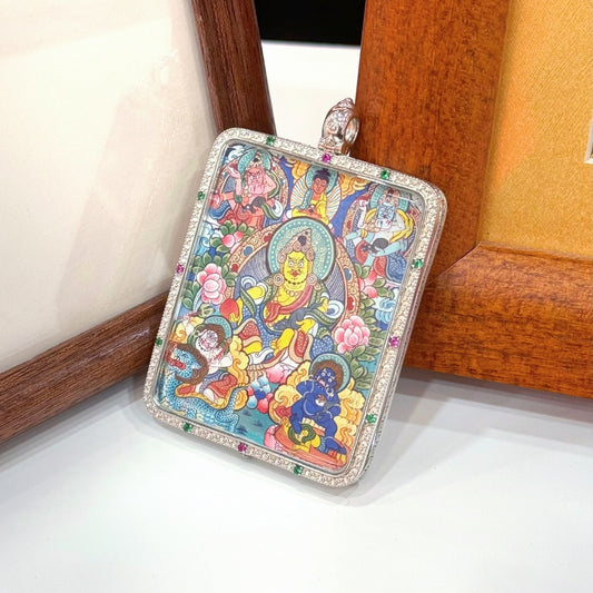 Angled front view of Five Jambhala mini thangka pendant showing the central Yellow Jambhala surrounded by the other four wealth deities, with lotus and cloud motifs, set in a silver gawu-style case with colored stone accents along the border.