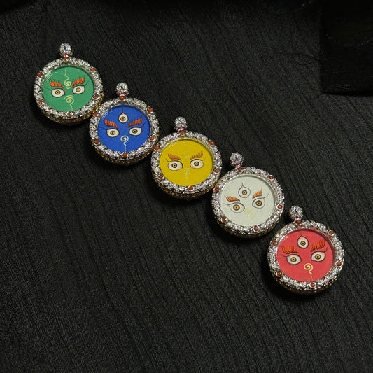Arrangement of five Jambhala wealth eye pendants in different elemental colors including green, blue, yellow, white, and red, miniature thangka paintings framed in jeweled copper cases.