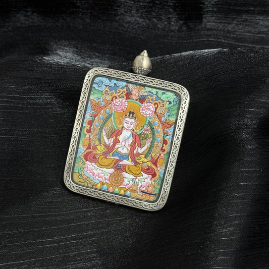 Front view of Four-Armed Avalokiteshvara Tibetan mini thangka pendant highlighting symmetrical four-arm posture, lotus base, halo ornamentation, mineral pigment layering, and detailed silver frame border.