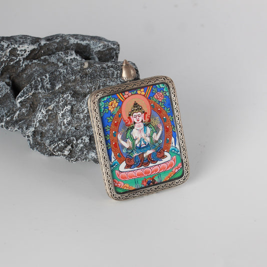Angled view of Four-Armed Avalokiteshvara mini thangka pendant showing engraved silver frame pattern, rounded corners, and top bail structure for wearing