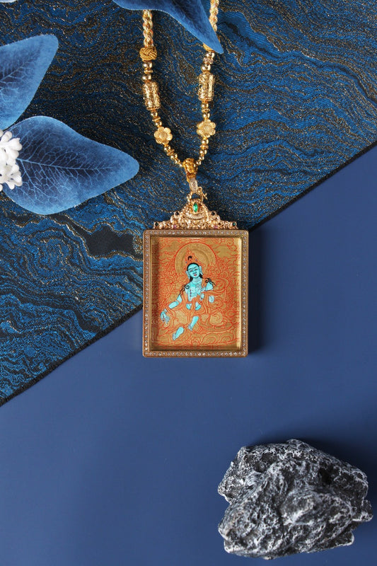 Hand-painted Green Tara mini thangka pendant on gold-ground background, square jewelry-style frame with crystal border, ornate top setting with green stone, beaded necklace display