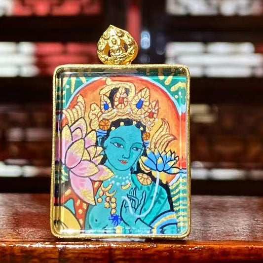 Front view of a double-sided hand-painted Gau Thangka pendant featuring Green Tara, crafted in an 18K gold case with sapphire crystal protection