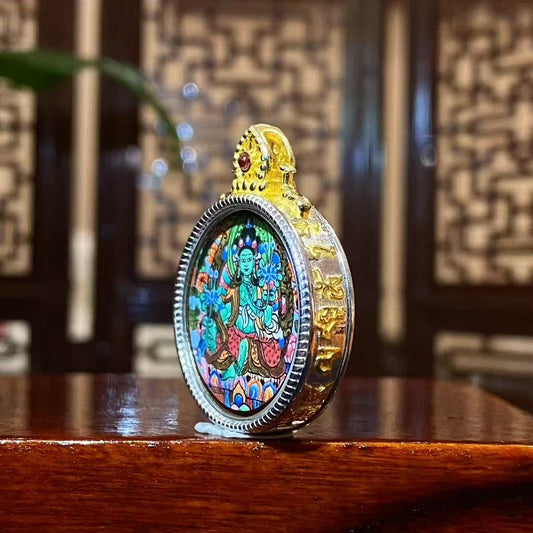 Side view of a hand-painted Green Tara thangka pendant with a complete seated image in an S925 silver Ghau box, 24 mm