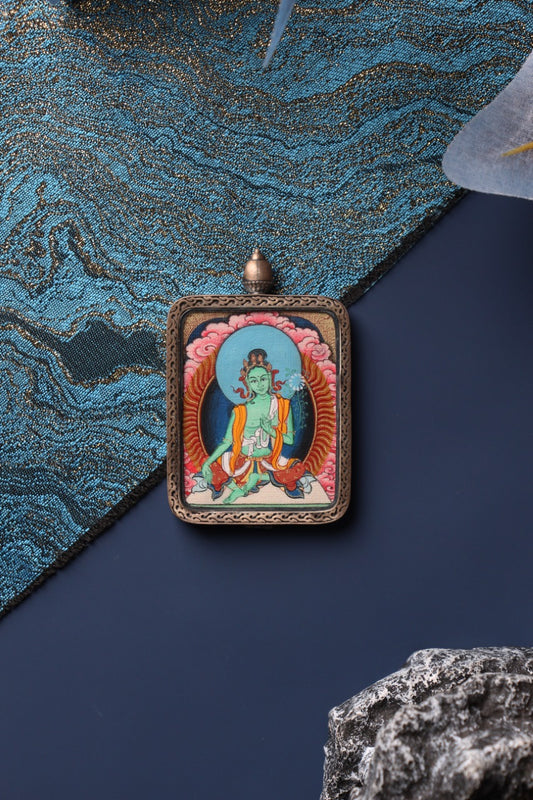 Front view of the Green Tara mini thangka pendant in Zangka format, a compact Tibetan devotional artwork hand-painted with mineral pigments and protected by a sterling silver case, suitable for travel devotion and personal shrine display.