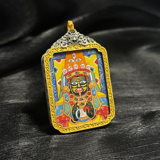 Angled view of Zaki Lhamo miniature thangka pendant showing vibrant mineral pigment painting, gold decorative frame, and intricate deity facial details.