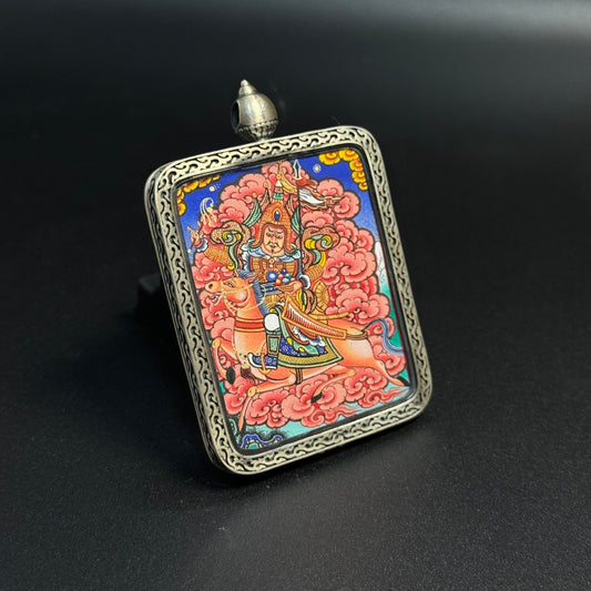 Angled view of King Gesar mini thangka pendant highlighting detailed warrior armor, horse figure and vibrant mineral pigment colors within a decorative sterling silver pendant frame.
