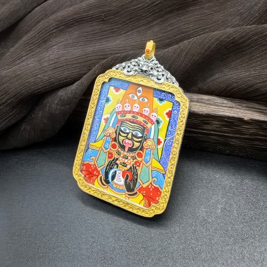Angled view of Zaki Lhamo Tibetan wealth protector mini thangka pendant showing vibrant mineral pigment painting, deity crown details and colorful background framed in a decorative pendant setting.
