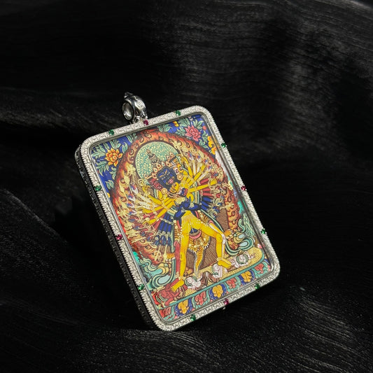 Angled view of Kalachakra mini thangka pendant showing hand-painted mineral pigment artwork inside silver protective frame