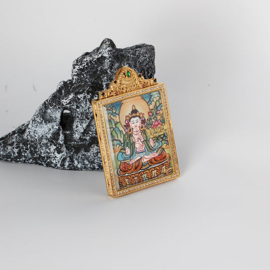Angled view of the Mahasthamaprapta Bodhisattva mini thangka pendant highlighting the crystal-set border, gold-tone case depth, and ornate crown top with green and multicolor stones, with the hand-painted artwork visible through the front window.
