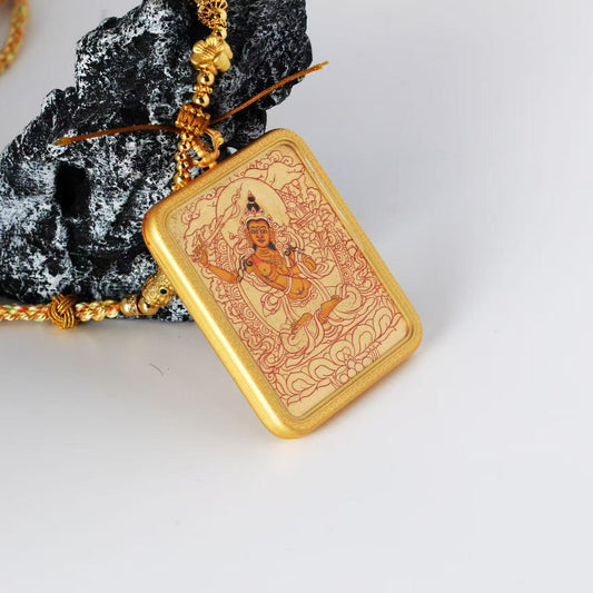 Angled view of the Manjushri Bodhisattva mini thangka pendant highlighting the thickness and edge of the copper case, the gold-ground painting surface, and the delicate linework details.