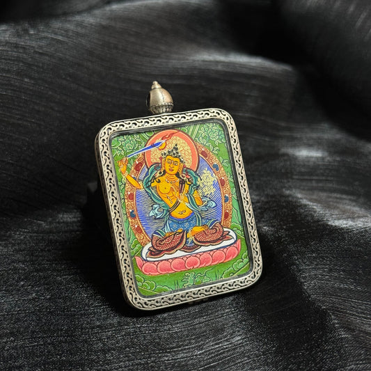 Angled view of Manjushri Bodhisattva mini thangka pendant highlighting detailed Tibetan hand-painted thangka art and ornate metal frame