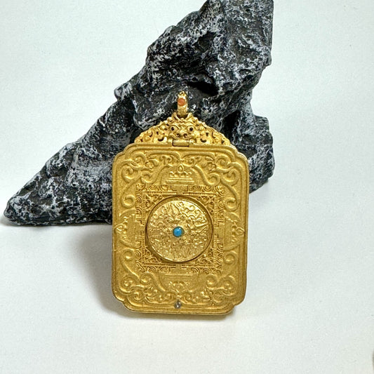 Back view of Nepal Black Gold Series pendant featuring an embossed mandala-style relief with a small turquoise-colored center accent and decorative scrollwork border.