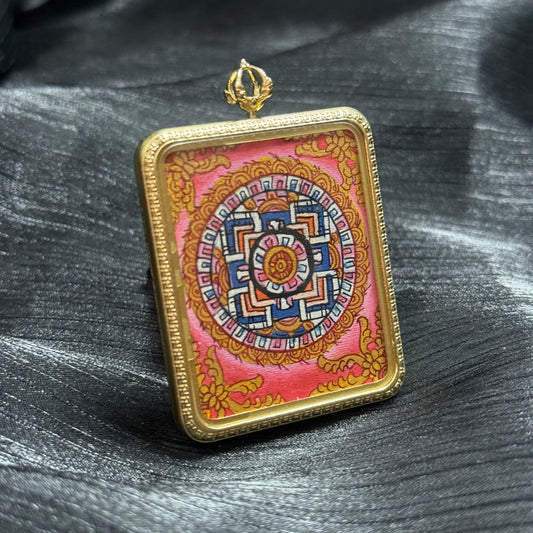 Angled view of a hand-painted mandala mini thangka pendant showing detailed Buddhist sacred geometry and colorful Himalayan thangka patterns.