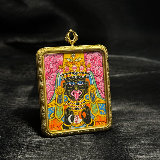 Side angle view of hand painted pink Zaki Lhamo mini thangka pendant from Nepal showing detailed deity portrait, bright mineral pigments and square gold frame on miniature portable Buddhist artwork.