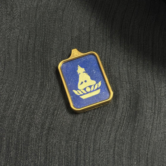 Angle view of a Rebgong hand-painted Formless Buddha mini thangka pendant showing the gold Buddha silhouette seated on a lotus against a shimmering lapis lazuli mineral pigment background.
