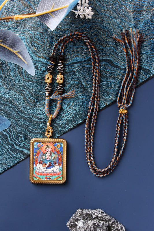 Samantabhadra Bodhisattva mini thangka pendant shown in full view, featuring the hand-painted deity image with mineral pigment colors, rectangular titanium steel case, raised border detailing, braided cord, bead section, and adjustable cord ends.
