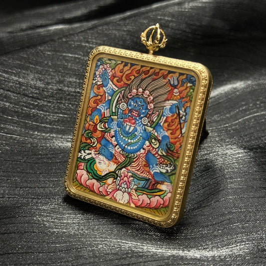 Close-up view of a Six-Armed Mahakala hand-painted thangka pendant, highlighting the expressive deity face, multiple arms, ritual implements, and vivid mineral pigment colors.