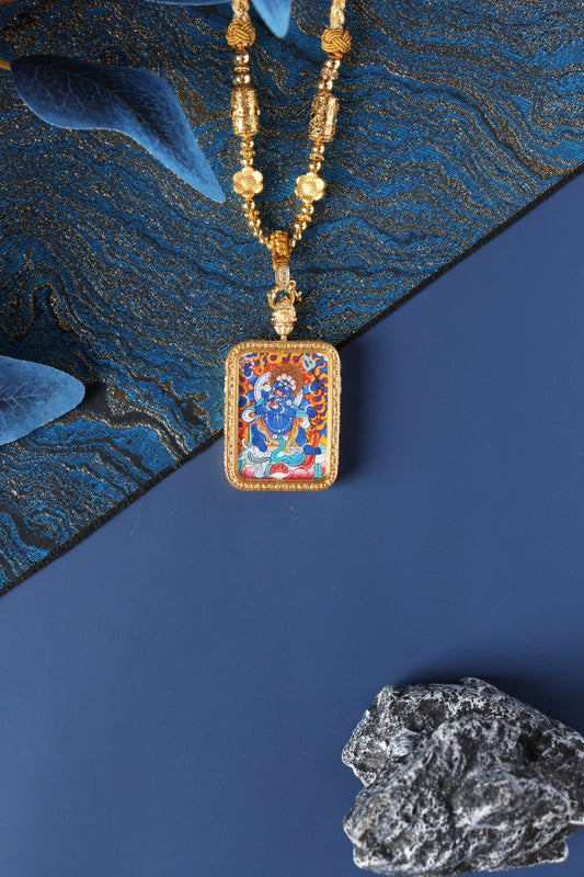 Hand-painted Six-Armed Mahakala mini thangka pendant displayed with gold-tone beaded necklace, rectangular double-sided metal case, mineral pigment artwork visible