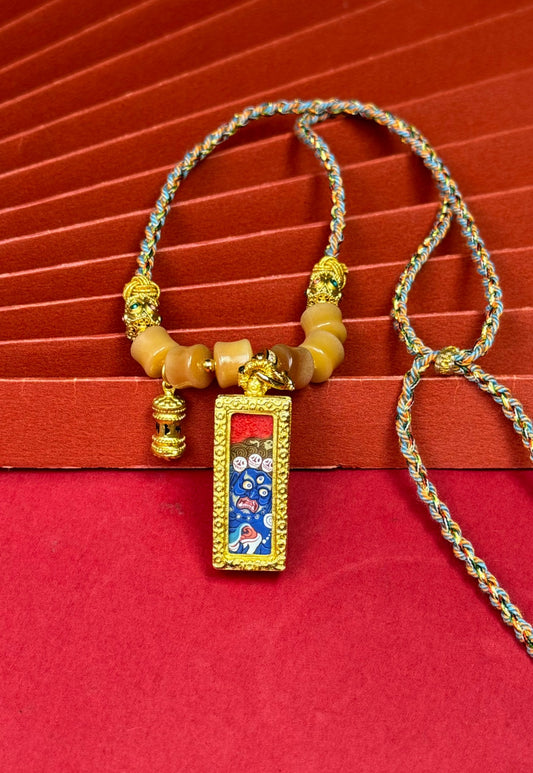 Close view of Six-Armed Mahakala mini thangka pendant with mineral pigment painting inside copper pendant case and handcrafted braided cord necklace