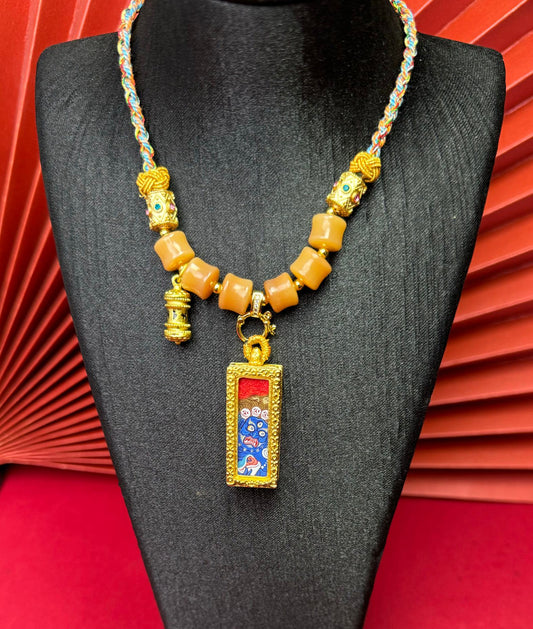 Six-Armed Mahakala miniature thangka pendant displayed on necklace stand, hand-painted Rebgong thangka artwork inside a decorative copper gawu pendant with braided Bodhi root cord