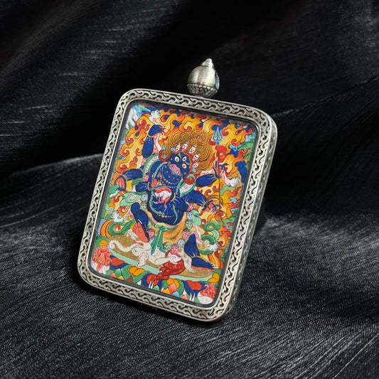 Angled view of Six-Armed Mahakala thangka pendant highlighting detailed mineral pigment painting, vivid flames and traditional Tibetan deity iconography inside a decorative silver frame