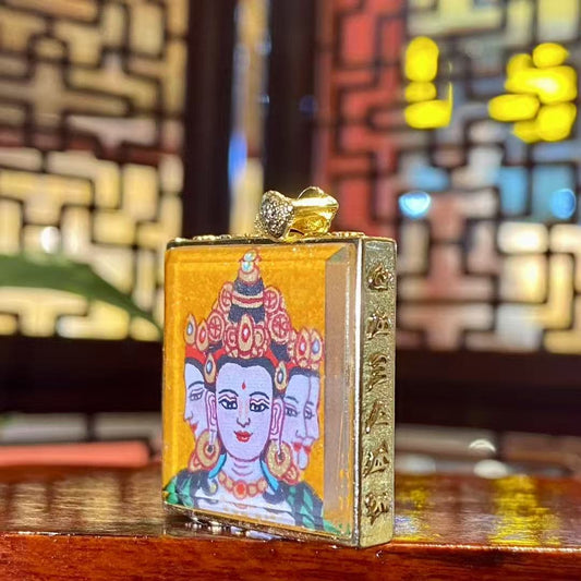 Close-up detail of a hand-painted Vairocana Buddha mini thangka pendant used as a Tibetan Buddhist amulet for wisdom and spiritual clarity