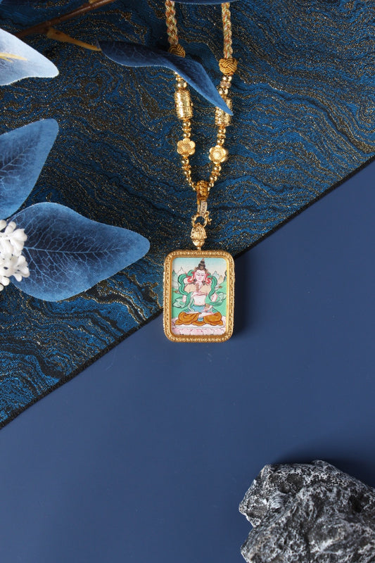 Hand-painted Vajrasattva mini thangka pendant displayed with gold-tone beaded necklace, rectangular double-sided titanium steel case, mineral pigment artwork visible