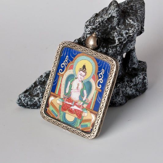 Centered front view of the Vajrasattva mini thangka pendant showing the carved silver border, top bail, and fine line detailing on the blue-ground painting.