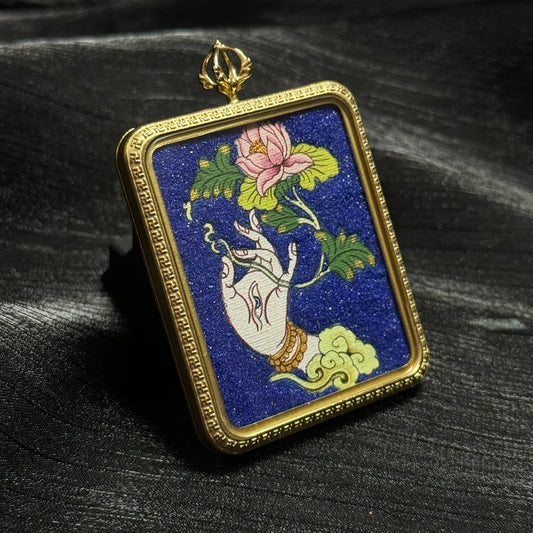Close-up angled view of a White Tara sacred hand holding a lotus flower, hand-painted miniature thangka pendant with detailed mineral pigment colors.