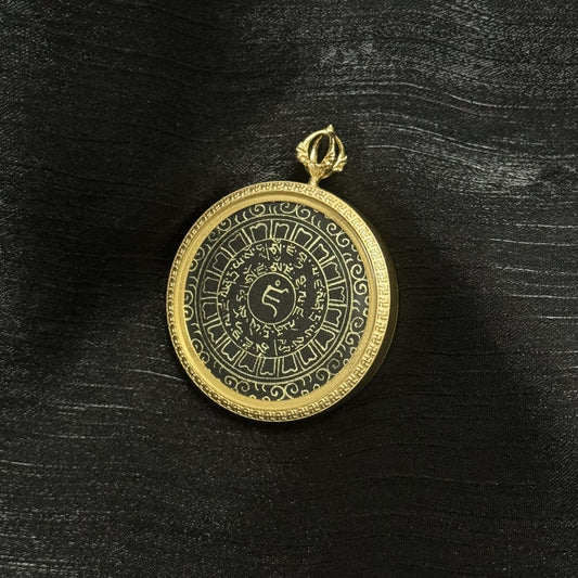 Full view of the Yellow Jambhala heart mantra pendant featuring concentric rings of Tibetan characters, central seed syllable, and a gold-tone frame with a decorative border.