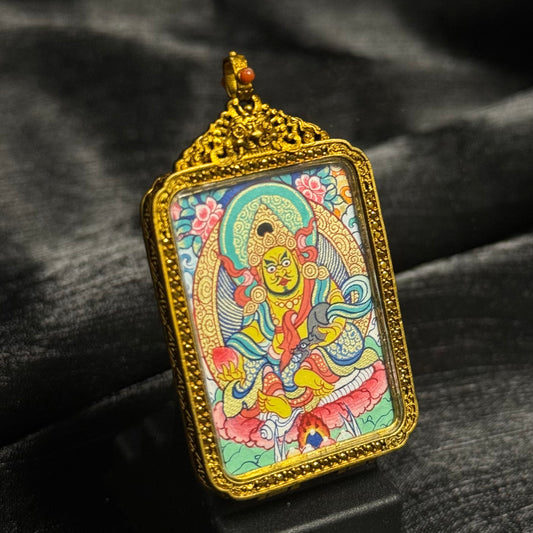 Angled view of a Yellow Jambhala miniature thangka pendant showing detailed Rebgong painting, vibrant mineral pigment colors, and an ornate Tibetan copper frame with decorative crown top.