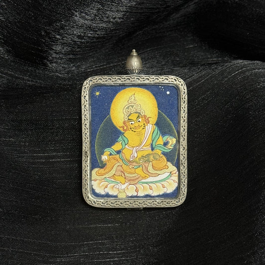 Front view of Yellow Jambhala mini thangka pendant, hand-painted with dense mineral pigments in Tibetan coarse mineral style, framed in a traditional silver protective case