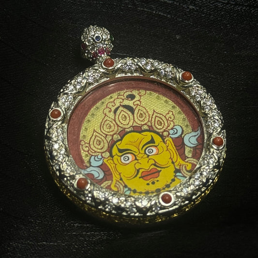 Front view of Yellow Jambhala mini thangka pendant featuring a hand-painted Rebgong thangka with cinnabar red background, gold halo details, and an ornate gemstone-set copper pendant frame.