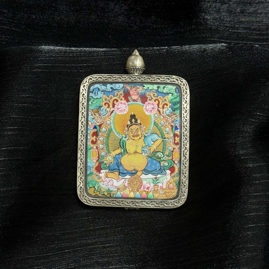 Front view of a fully hand-painted Yellow Jambhala mini thangka pendant set in a Dunhuang Nine-Color Deer silver gawu case, featuring mineral pigment detailing, ornate silver frame, and vibrant Tibetan iconography.